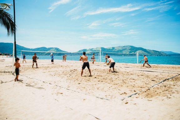 group playing beach volleyball by the lake