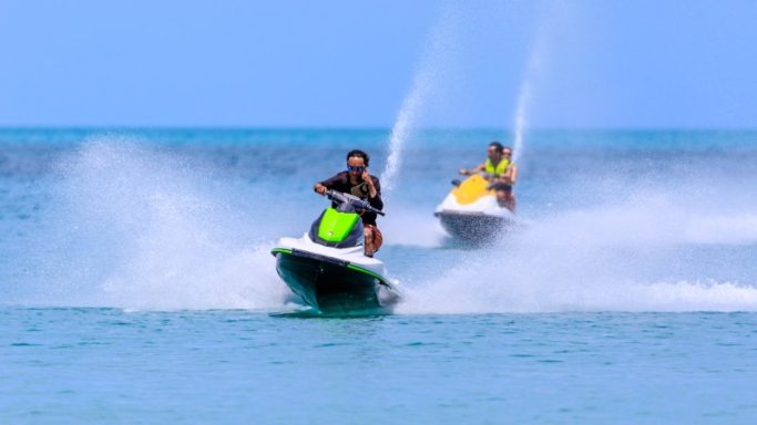 2 people on 2 separate jet skis riding on the lake